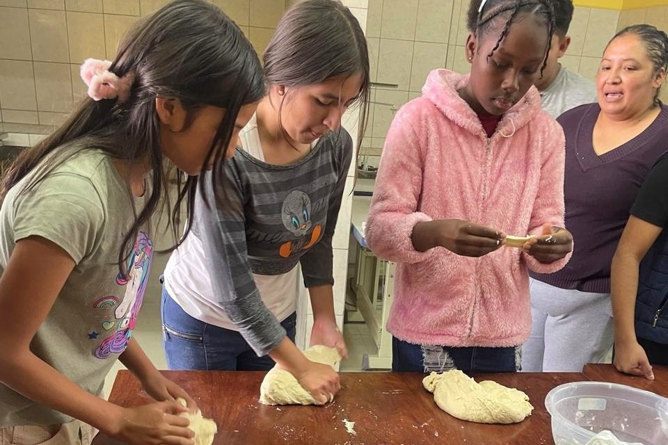 Young People Building Leadership, Creativity and Community in Pifo, Ecuador | Photo: Danielle Children's Fund Ecuador | Image provided to KJCF by Danielle Children's Fund Young people work together around a table during a hands-on activity at the Pifo Youth Club in Ecuador. Participants prepare dough while learning and collaborating in a shared community space. The club supports adolescents in developing personal, social and creative skills and strengthening their leadership within the community.