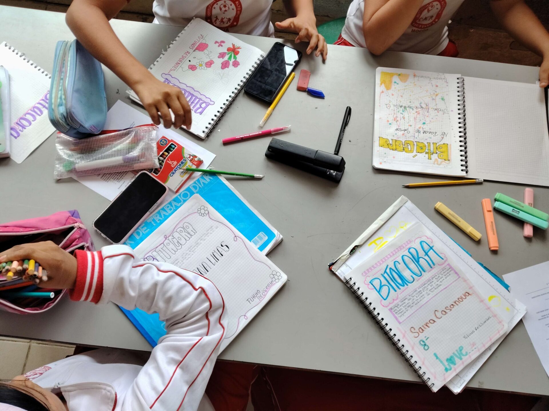 Young People Reflecting on Their Futures Through Creative Learning and Personal Development in Colombia | Photo: War Child | Image provided by War Child Notebooks filled with handwritten reflections, drawings and colourful decorations lie open on a table surrounded by school supplies, pens and pencils during a creative workshop in Colombia. The journals are used by young participants to explore their dreams, values, inspirations and future goals as part of a personal development and life-planning activity.