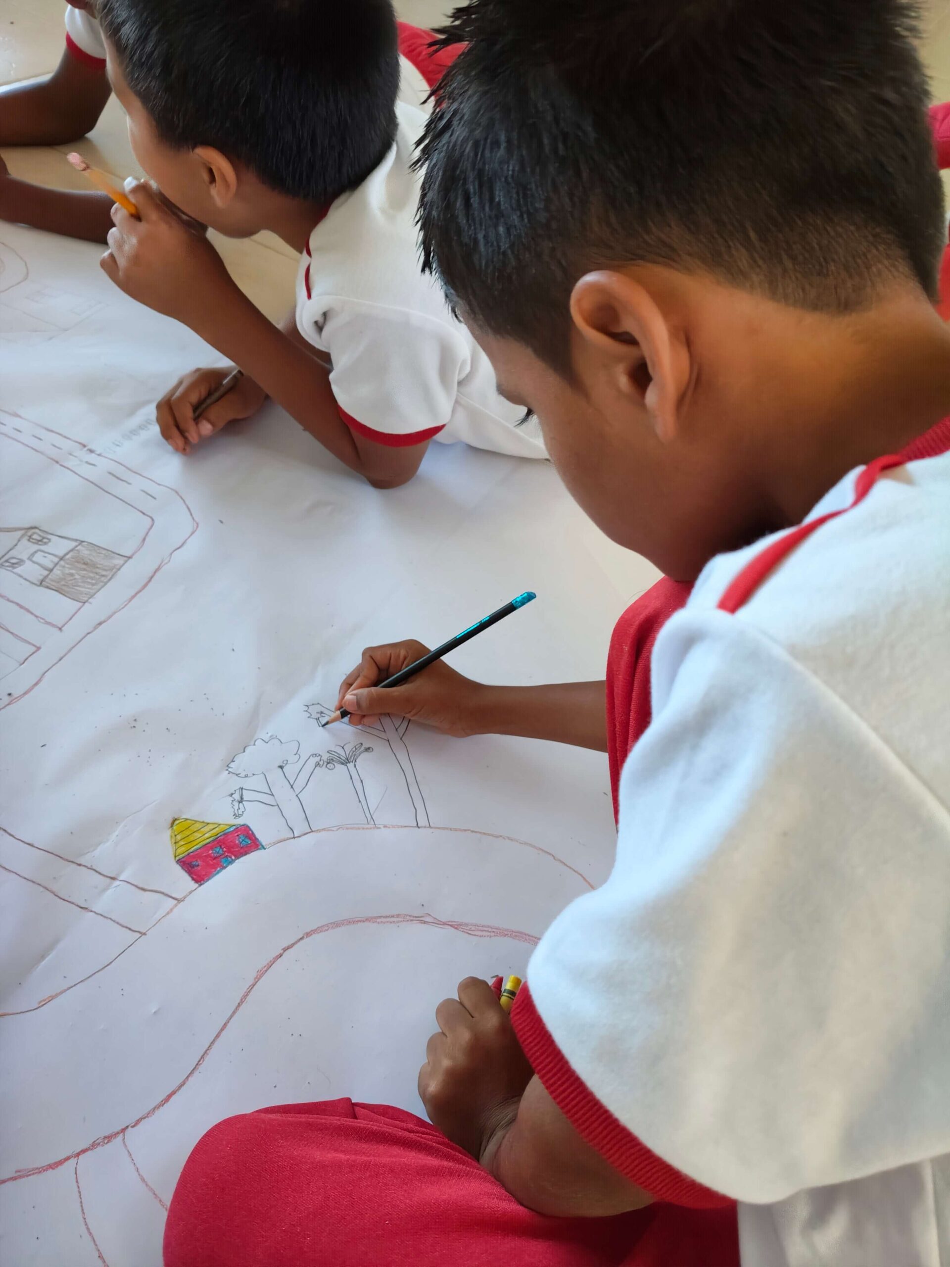 Children Mapping Community Risks and Safety Concerns to Strengthen Protection in Colombia | Photo: War Child | Image provided by War Child Children work together on a large hand-drawn community map, sketching roads, homes, trees and local landmarks during a participatory risk-mapping exercise. The activity helps identify safety concerns affecting their community, including traffic risks linked to National Highway No. 45 and broader social and environmental challenges.