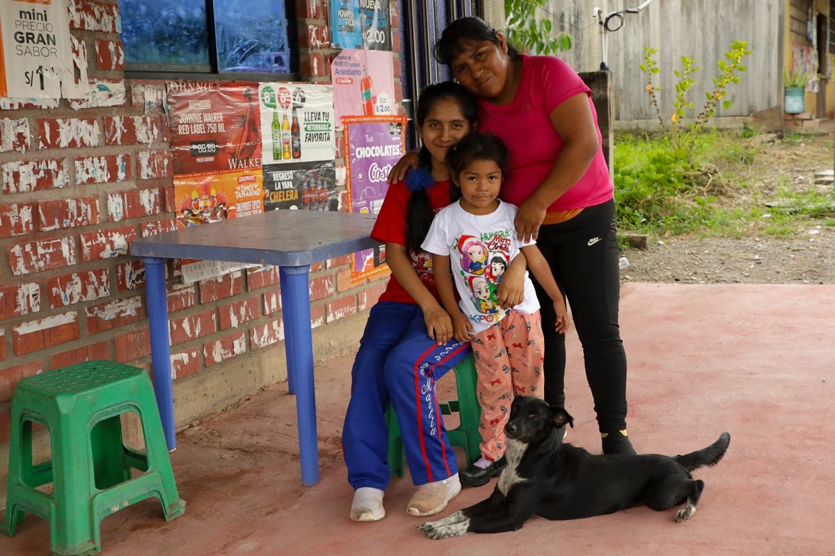 La historia de Katti y Natali destaca la importancia del apoyo familiar para niñas y niños con parálisis cerebral en Perú | Foto: Sense International Perú | Imagen proporcionada por Sense International Katti se encuentra junto a su hija Natali, quien tiene parálisis cerebral, y otra niña frente a su vivienda en Perú. La familia posa en un espacio exterior junto a una casa de ladrillo mientras un perro descansa a sus pies. La imagen refleja la importancia del apoyo familiar y de los servicios inclusivos para el desarrollo y la participación de niñas y niños con discapacidad.
